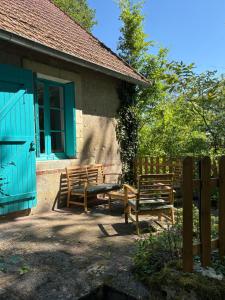 two benches sitting outside of a house with a fence at Cottage de La Meslerie in Vernou-sur-Brenne