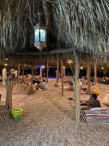 a group of people laying on the beach under a straw hut at La Basha Camp in Dahab