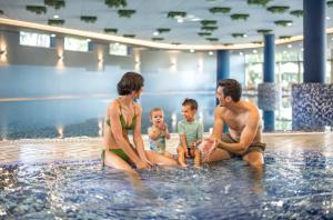 a family sitting in the water in a swimming pool at Remisens Hotel LUCIJA in Portorož