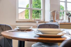 a wooden table with two wine glasses and plates on it at Zeitlos Wriezen 2 in Wriezen