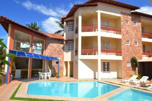 a villa with a swimming pool in front of a building at Hotel Brisa dos Abrolhos in Alcobaça