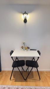 a white table with two chairs and a light on a wall at Modern Mini Apartment in Malmö