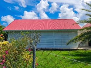 a house with a red roof and a fence at Maison accueillante à Anse-Bertrand avec jardin privé 70 m² in Anse-Bertrand
