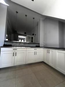 a large white kitchen with white cabinets and appliances at Dwór Grabina in Ciechomice