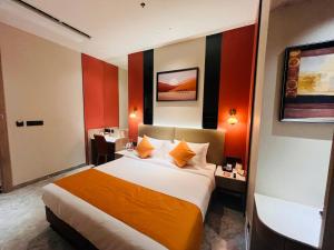 a hotel room with a bed with an orange blanket at Ira By Orchid Bhavnagar in Bhavnagar