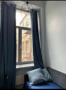 a window with a blue curtain and a couch in a room at Cozy Loft Studio, one open space, in great location in Vilnius