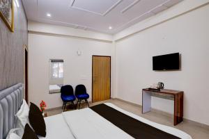 a hotel room with a bed and two blue chairs at Hotel Palm Paradise in Noida +7 photos