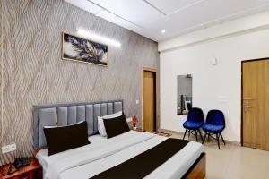 a bedroom with a bed and two blue chairs at Hotel Palm Paradise in Noida