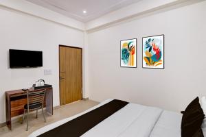 a bedroom with a bed and a desk and a television at Hotel Palm Paradise in Noida