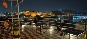 a man sitting at a table on a balcony at night at Hotel Lake Star Bistro in Udaipur