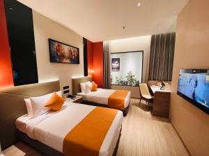 a hotel room with two beds and a flat screen tv at Ira By Orchid Bhavnagar in Bhavnagar