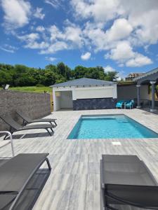 a swimming pool with chaise lounges and chairs at VILLA Orchidée in Le Moule