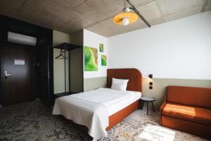 a bedroom with a bed and a chair at Arche Hotel Wrocław Airport in Wrocław