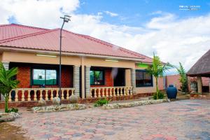 a building with a red roof and a cobblestone street at 7Palms Executive Lodges in Ndola