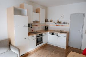a kitchen with white cabinets and a stove top oven at Claes Weinquartier - Appartements & Wein by Niko Schmitt in Trittenheim