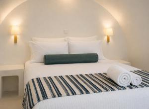 a bedroom with a white bed with towels on it at Santorini Theasis Suites in Imerovigli +50 photos