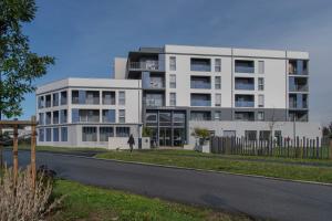 a woman standing in front of a white building at DOMITYS - Les Quernons in Trélazé