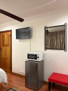 a room with a tv and a microwave on a wall at Tsheryl's Residence in Centurion