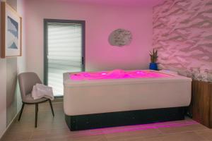 a pink room with a tub with pink lighting at DOMITYS - Les Quernons in Trélazé +7 photos