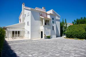 a large white house with a driveway at Apartments & Rooms Petra in Zadar