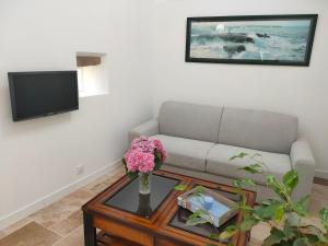 a living room with a couch and a table with flowers at Authentic Breton penty in Penmarch