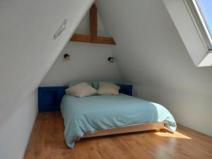 a bedroom with a blue bed in a attic at Authentic Breton penty in Penmarch
