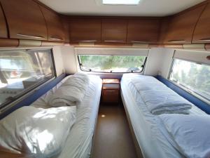 a small room with two beds and two windows at The Sûre & Simple Caravan in Houschthauser +19 photos