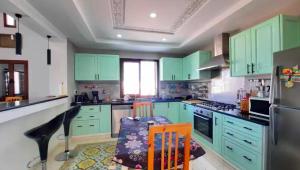 a kitchen with green cabinets and a table and chairs at Dar amiratt in El Guecheïne