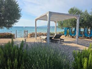 a chair under a gazebo next to the ocean at Villa Beach Charly in Tisno