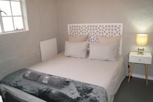a bedroom with a bed with white sheets and pillows at Chalet Duiker in Ladismith