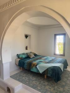 a bed in a white room with an arch at Dar amiratt in El Guecheïne +11 photos