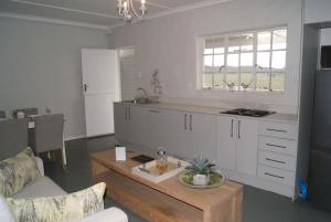 a kitchen with white cabinets and a table in a room at Chalet Duiker in Ladismith