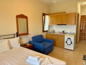 a bedroom with a bed and a blue chair and a kitchen at Artion Studios in Vourvourou