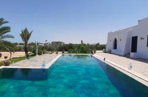 a swimming pool with blue water in front of a building at Dar amiratt in El Guecheïne