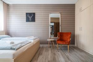 a bedroom with a bed and a chair and a mirror at AH-Corso Wellness Residence in Siófok +74 photos