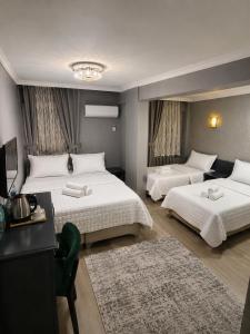 a bedroom with two beds and a desk and a television at Çorlu Aras Hotel & City Center Location in Çorlu