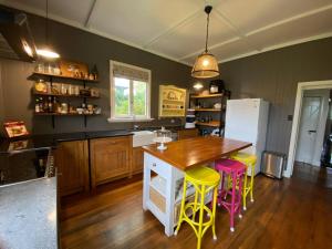 a kitchen with a wooden table and yellow stools at Awen Cottage in Tenterfield