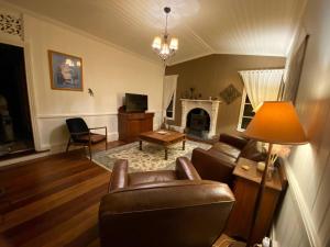 a living room with leather furniture and a fireplace at Awen Cottage in Tenterfield