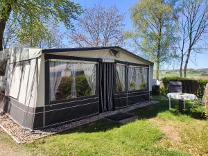 a black greenhouse in the grass with a chair at The Sûre & Simple Caravan in Houschthauser