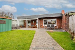 a brick house with a patio and a lawn at Bungalow Windsbraut in Norddeich