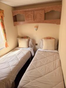 two beds in a small room with white sheets at Swans Rest - Lakeside Caravan Park in Denver