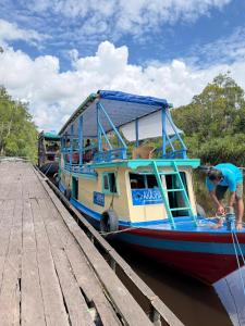 a man standing next to a boat at a dock at Kelotok Orangutan Tanjung Puting in Kumai