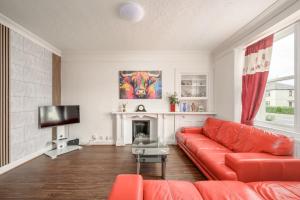 a living room with a red couch and a tv at Bosta Guest House - Private Rooms - Inverness in Inverness
