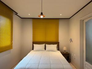 a bedroom with a bed with white sheets and a yellow window at 차북차북 in Kwakchi-ri
