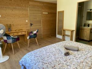 a bedroom with a bed and a desk and chairs at Du Baume Au Cœur in Baume-les-Messieurs