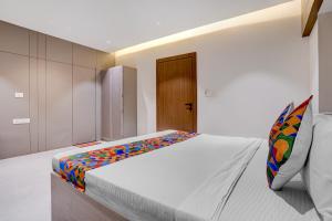 a bedroom with a white bed with a colorful pillow at FabHotel Vaishnav Bairagi in Nashik