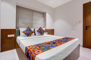 a bedroom with a large bed with a colorful blanket at FabHotel Vaishnav Bairagi in Nashik