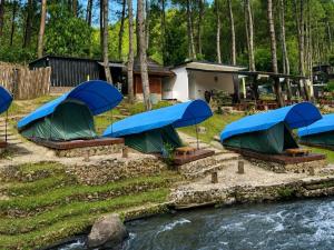 a group of tents sitting next to a river at Batupineus Riverside in Palayangan