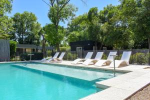 a swimming pool with white lounge chairs next to it at Monte Aromas Casas en la Naturaleza Roldán in Roldán