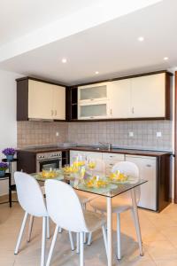 a kitchen with a dining room table with white chairs at Corfu Dream Holidays Villas in Glyfada